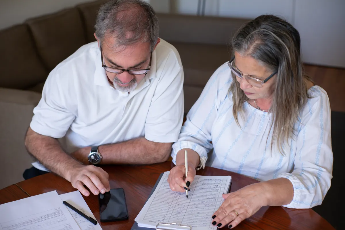 Two adults reviewing documents and a smartphone at a table