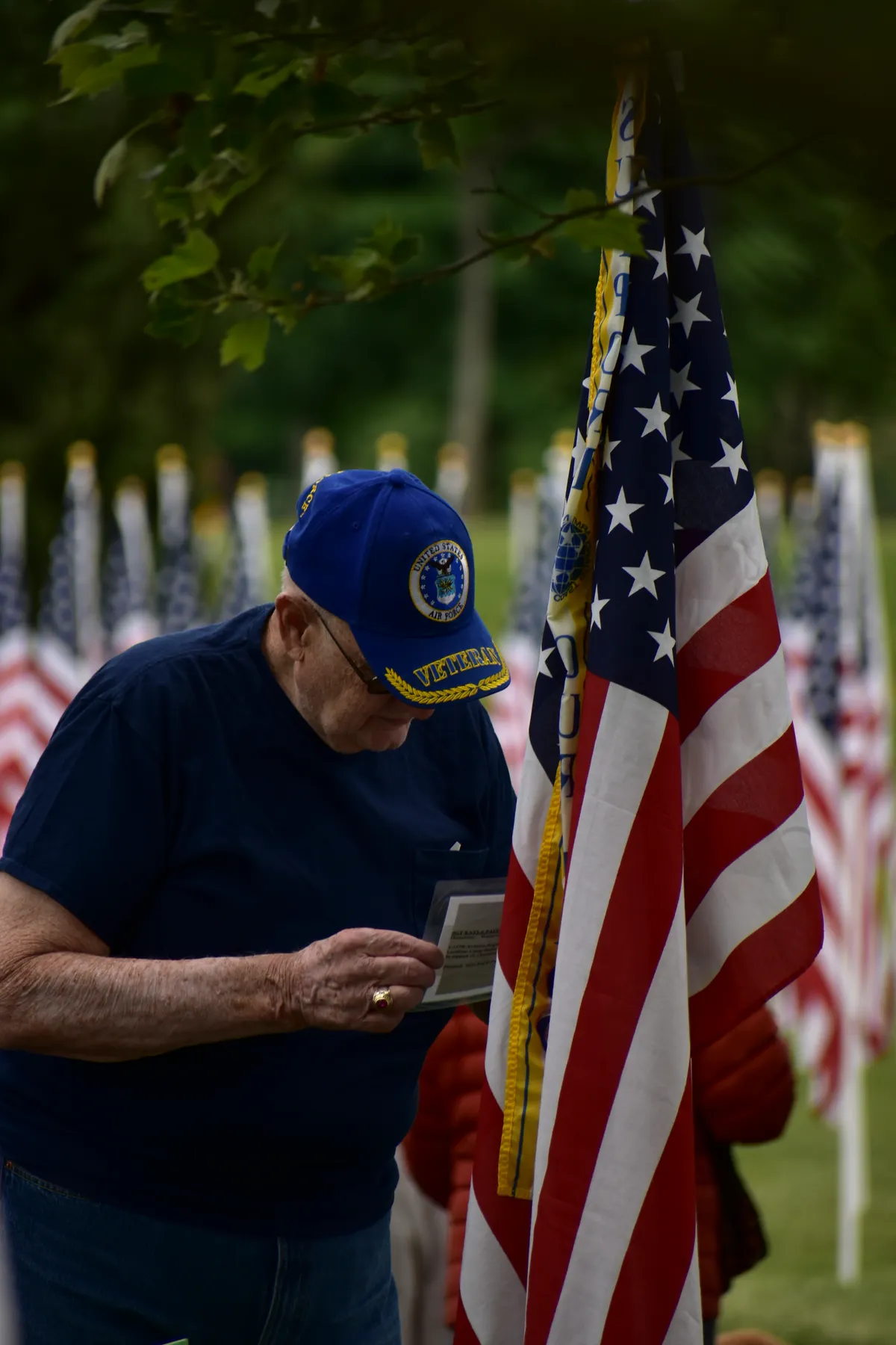An older man standing beside an American flag outdoors
